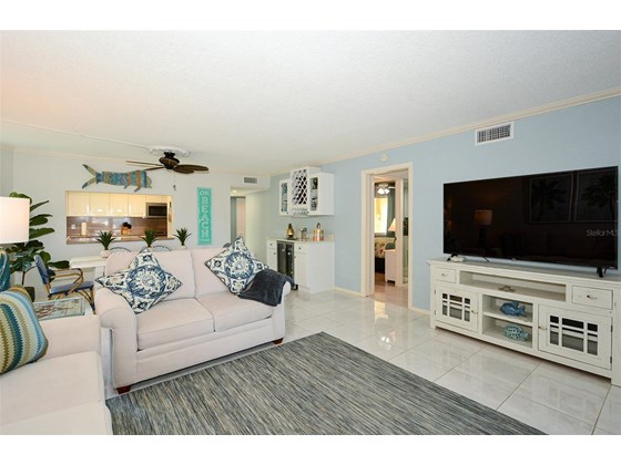 Living room to dining with dry bar and wine refrigerator.  Bedroom 2 visible through hallway. Pocket door for privacy - Condo for sale at 450 Gulf Of Mexico Dr #B107, Longboat Key, FL 34228 - MLS Number is A4520786